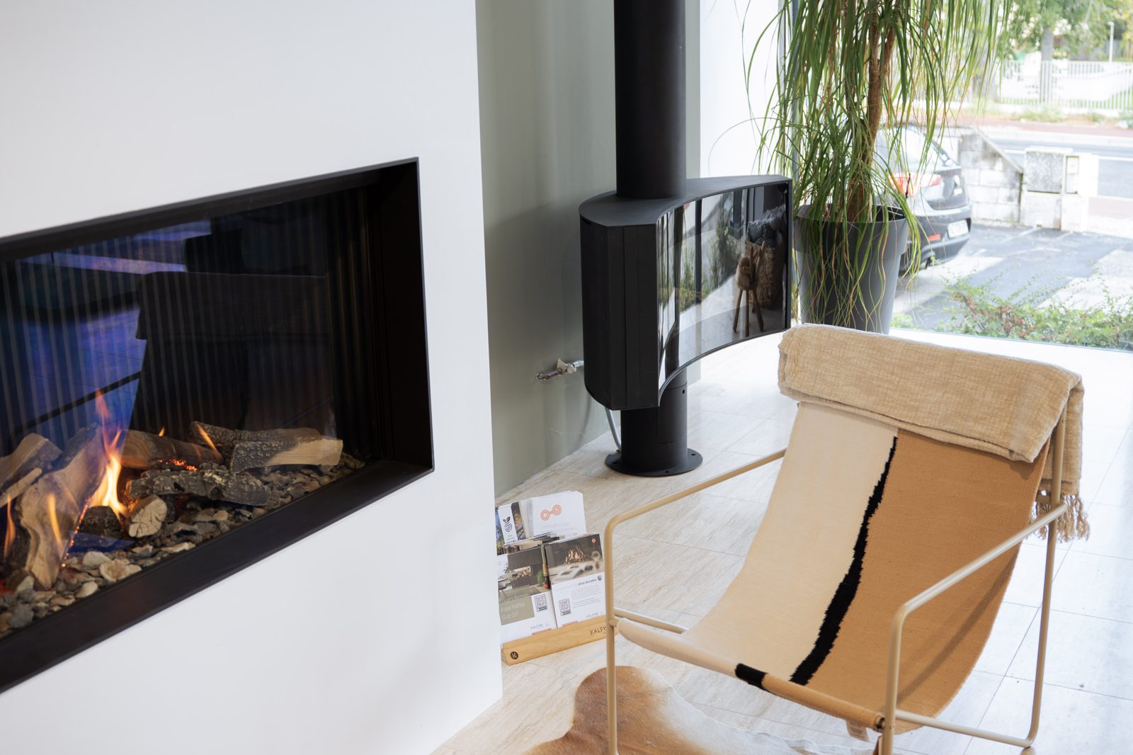 Foyer gaz linéaire et poêle suspendu devant la baie du showroom Sparte à Toulouse
