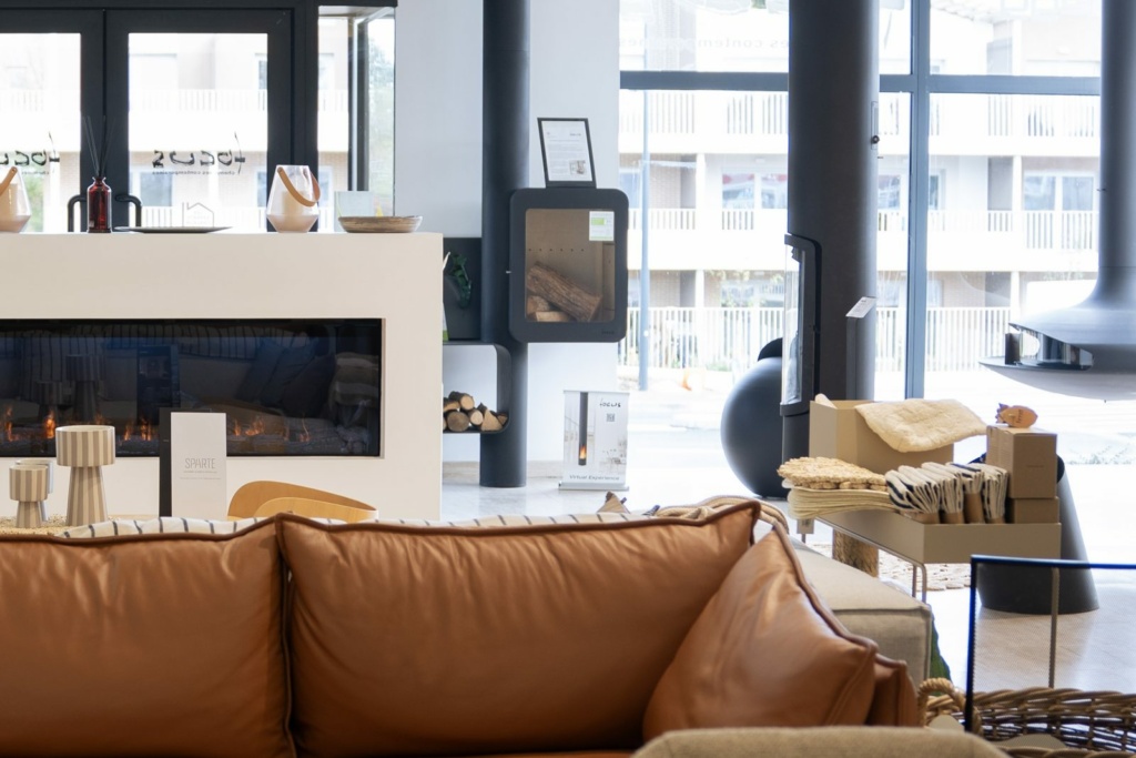 Canapé en cuir et foyer linéaire devant la baie du showroom Sparte à Toulouse