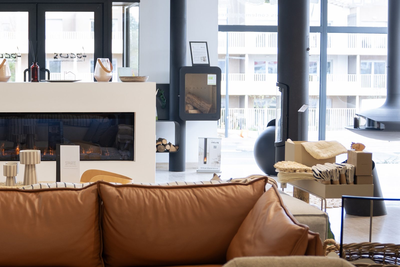 Canapé en cuir et foyer linéaire devant la baie du showroom Sparte à Toulouse